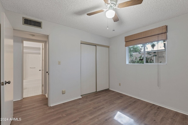 unfurnished bedroom featuring baseboards, visible vents, wood finished floors, a textured ceiling, and a closet