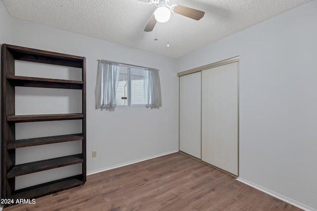 unfurnished bedroom with baseboards, ceiling fan, wood finished floors, a textured ceiling, and a closet