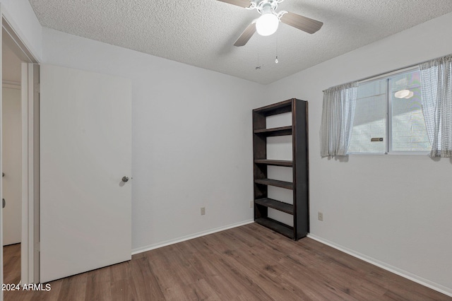 unfurnished room featuring ceiling fan, a textured ceiling, baseboards, and wood finished floors