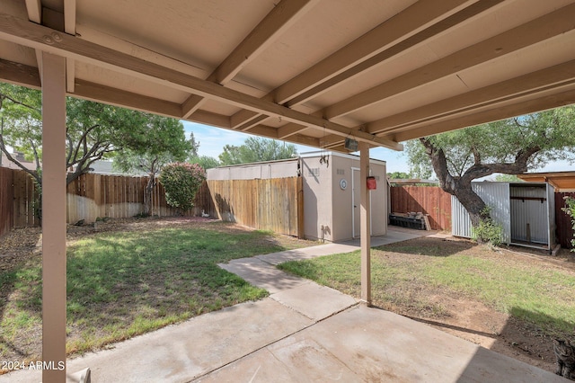 view of yard featuring a fenced backyard, a storage unit, a patio, and an outdoor structure