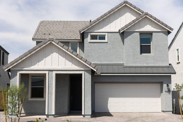 view of front of property with an attached garage, a tile roof, decorative driveway, board and batten siding, and a standing seam roof