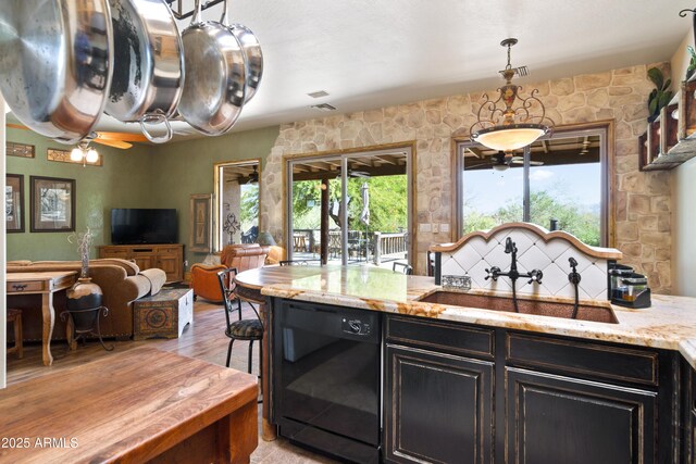 21909 W Beacon Ln, Wittmann, AZ 85361 - kitchen featuring hanging light fixtures, a sink, light stone counters, open floor plan, and black dishwasher