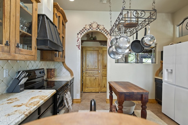 21909 W Beacon Ln, Wittmann, AZ 85361 - kitchen featuring white refrigerator with ice dispenser, light tile patterned flooring, black / electric stove, and premium range hood