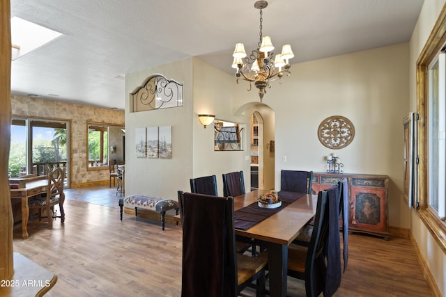 21909 W Beacon Ln, Wittmann, AZ 85361 - dining area featuring arched walkways, baseboards, wood finished floors, and a chandelier