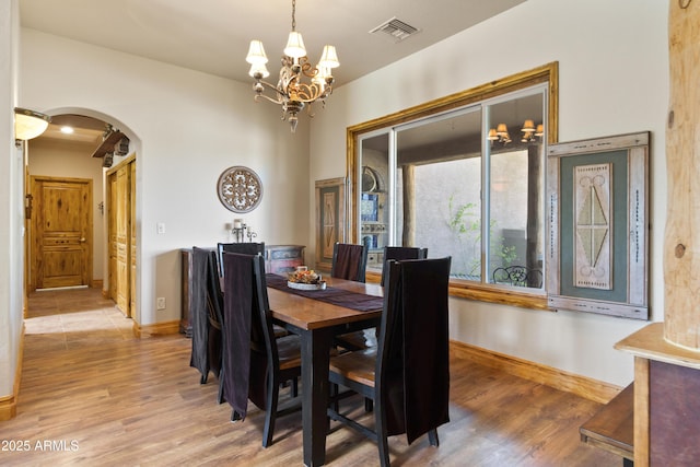 21909 W Beacon Ln, Wittmann, AZ 85361 - dining area with visible vents, arched walkways, baseboards, a notable chandelier, and light wood-style flooring