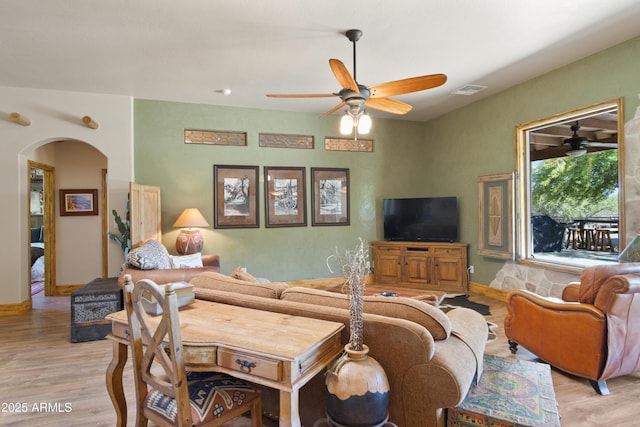 21909 W Beacon Ln, Wittmann, AZ 85361 - living room with light wood-style floors, arched walkways, ceiling fan, and baseboards