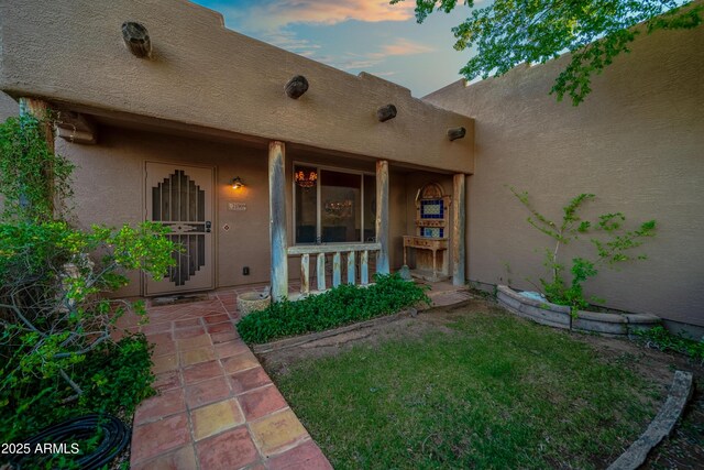 21909 W Beacon Ln, Wittmann, AZ 85361 - exterior entry at dusk featuring stucco siding and a porch