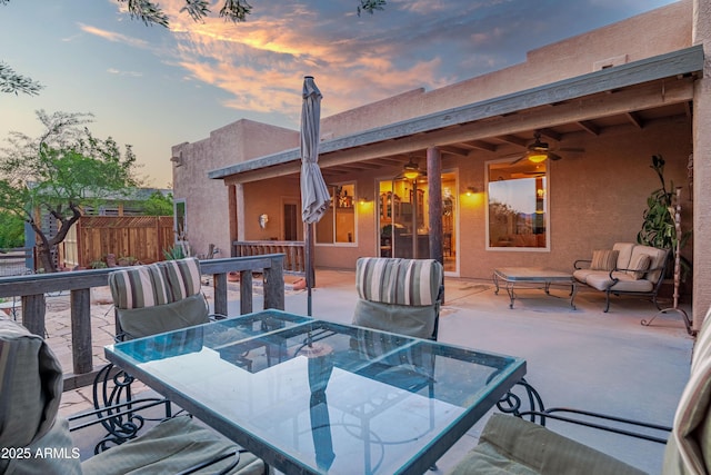 21909 W Beacon Ln, Wittmann, AZ 85361 - deck at dusk featuring outdoor dining area, a ceiling fan, a patio area, and fence