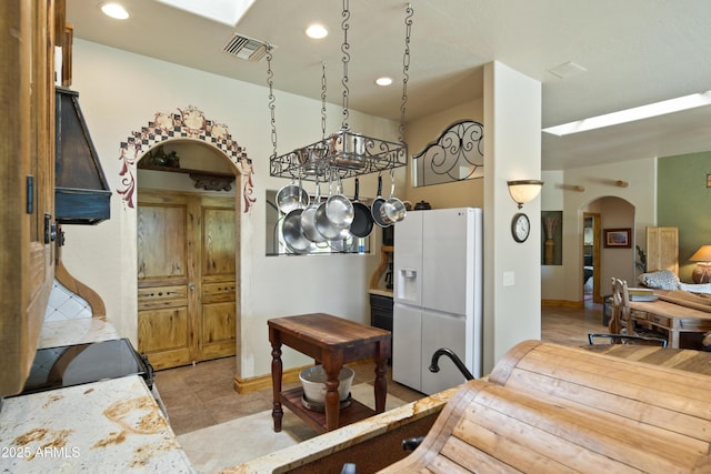21909 W Beacon Ln, Wittmann, AZ 85361 - kitchen with arched walkways, white refrigerator with ice dispenser, recessed lighting, and visible vents