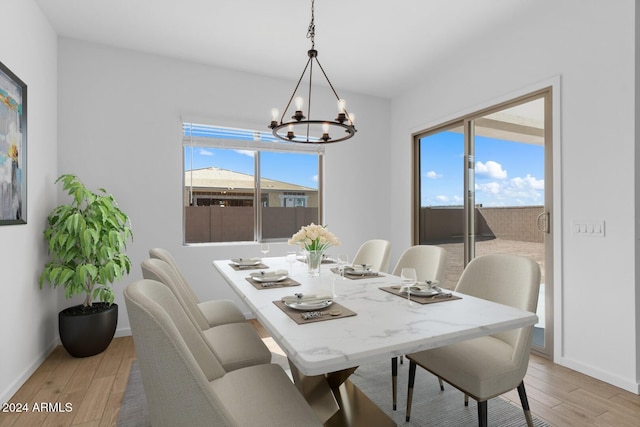 dining area with light wood-type flooring, a notable chandelier, and baseboards