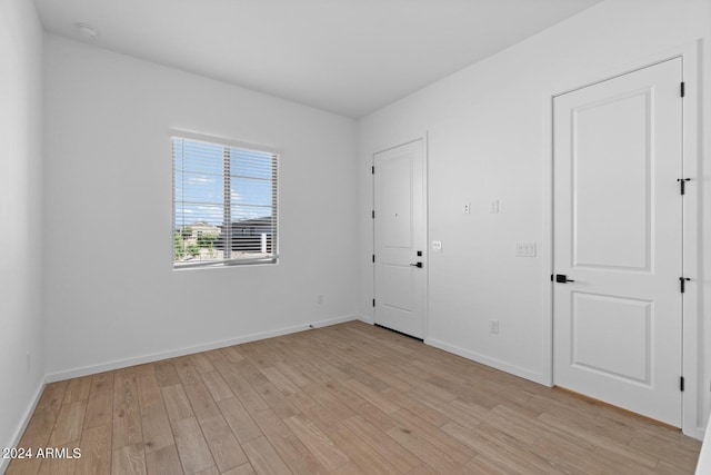 empty room featuring light wood-type flooring and baseboards