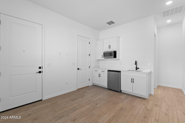 kitchen featuring appliances with stainless steel finishes, light wood-style floors, visible vents, and a sink