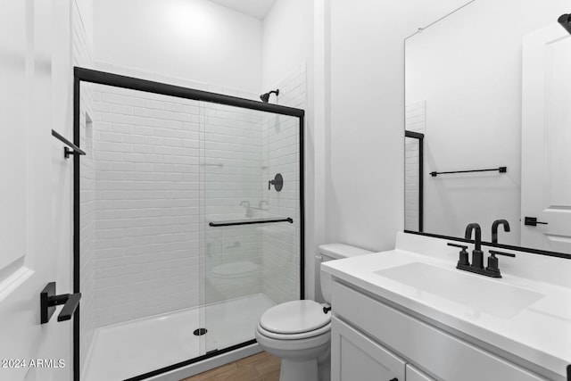 bathroom featuring a stall shower, vanity, toilet, and wood finished floors