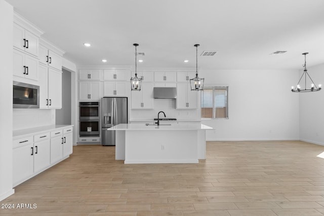 kitchen with under cabinet range hood, visible vents, stainless steel appliances, and a notable chandelier