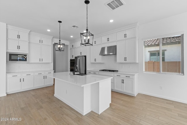 kitchen featuring appliances with stainless steel finishes, a kitchen island with sink, visible vents, and under cabinet range hood