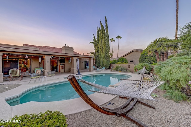 pool at dusk with a patio