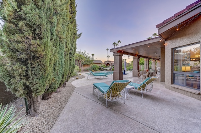 patio terrace at dusk with a fenced in pool