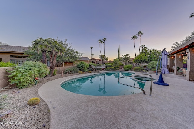 pool at dusk featuring a patio