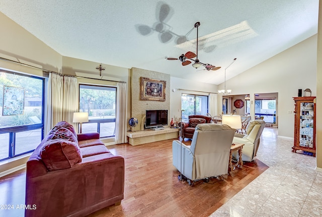 living room featuring a textured ceiling, a notable chandelier, a fireplace, high vaulted ceiling, and hardwood / wood-style floors