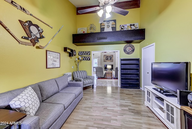 living room with a high ceiling, ceiling fan, and light hardwood / wood-style flooring