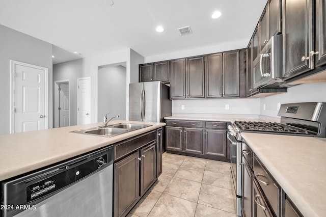 kitchen featuring sink, light tile patterned floors, stainless steel appliances, and dark brown cabinets