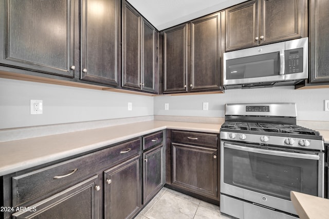 kitchen featuring dark brown cabinets, light tile patterned floors, and appliances with stainless steel finishes