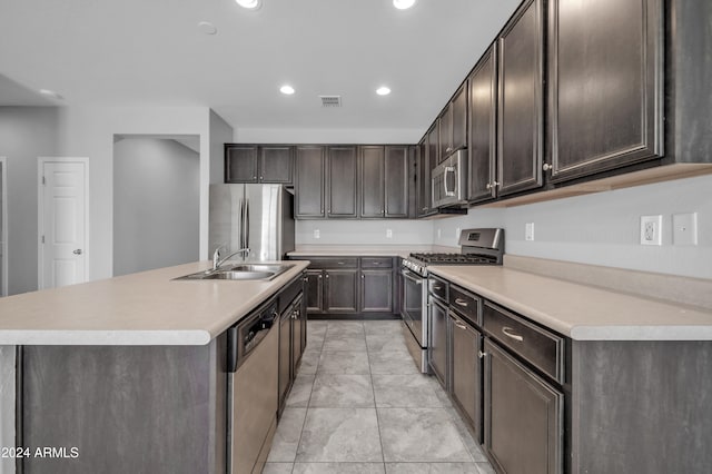 kitchen featuring dark brown cabinetry, sink, stainless steel appliances, and a center island with sink