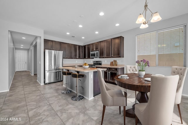 kitchen featuring decorative light fixtures, a kitchen bar, dark brown cabinets, a kitchen island, and appliances with stainless steel finishes