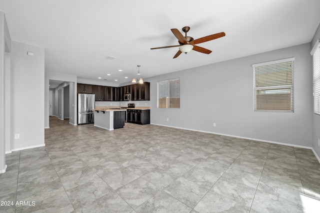 unfurnished living room featuring ceiling fan with notable chandelier