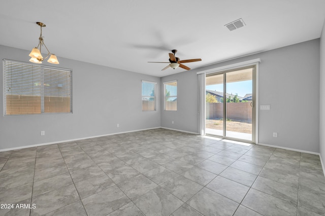 spare room featuring light tile patterned floors and ceiling fan with notable chandelier