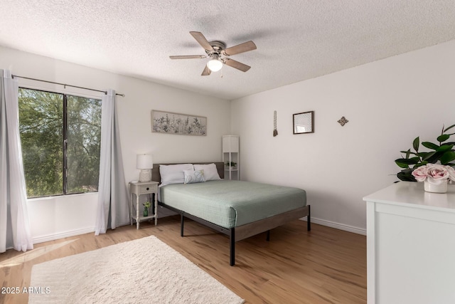 4950 N Miller Rd Unit 200, Scottsdale, AZ 85251 - bedroom with light wood finished floors, a textured ceiling, baseboards, and ceiling fan