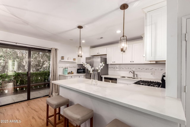 4950 N Miller Rd Unit 200, Scottsdale, AZ 85251 - kitchen with appliances with stainless steel finishes, a peninsula, white cabinets, decorative backsplash, and a sink
