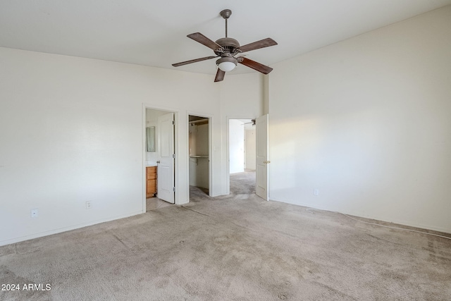 unfurnished bedroom with a closet, light colored carpet, ensuite bath, and ceiling fan