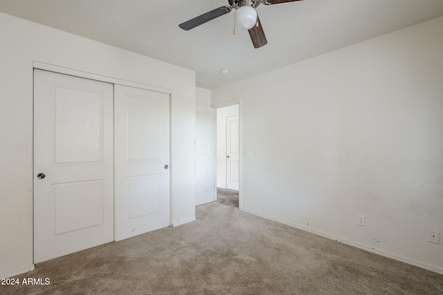 unfurnished bedroom with ceiling fan, light colored carpet, and a closet