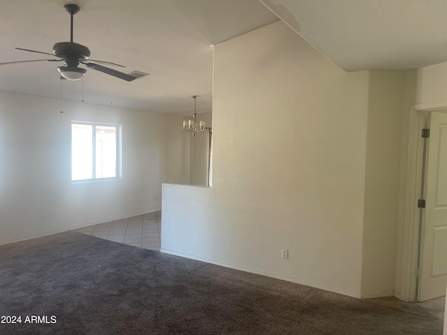 spare room featuring ceiling fan with notable chandelier and light colored carpet