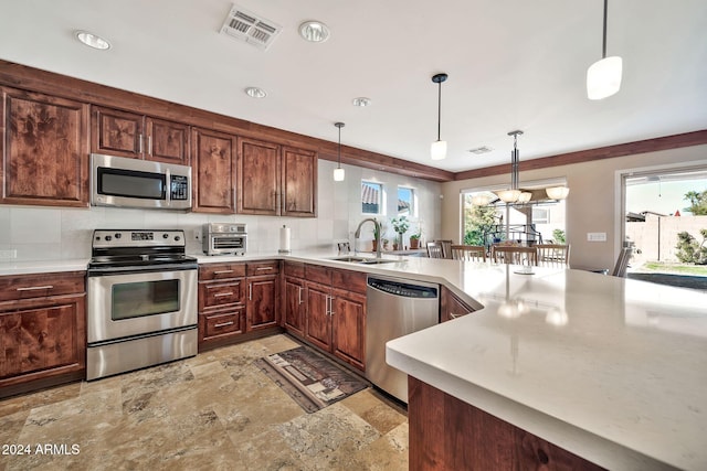 kitchen featuring sink, decorative light fixtures, and appliances with stainless steel finishes