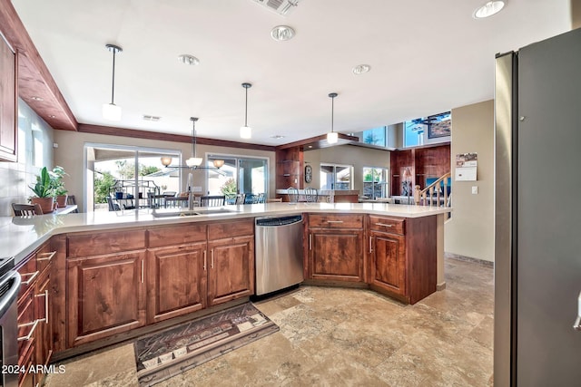 kitchen with sink, hanging light fixtures, an inviting chandelier, kitchen peninsula, and appliances with stainless steel finishes