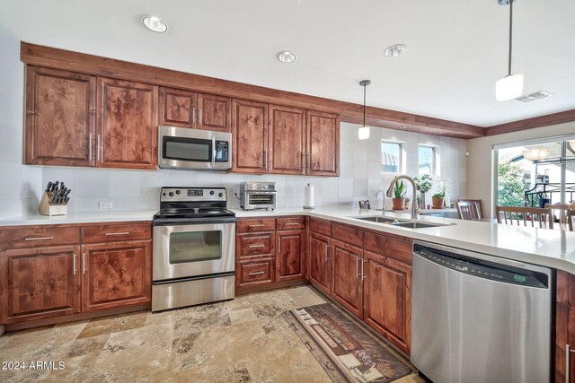 kitchen with decorative backsplash, pendant lighting, stainless steel appliances, and sink