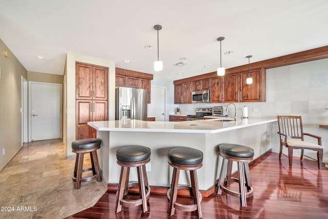 kitchen featuring kitchen peninsula, appliances with stainless steel finishes, dark hardwood / wood-style flooring, sink, and hanging light fixtures