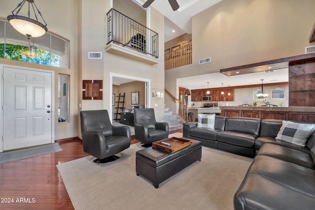 living room with a towering ceiling, ceiling fan, and dark hardwood / wood-style floors