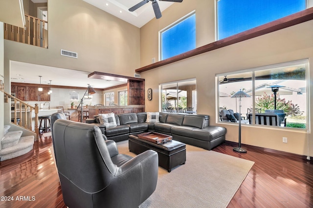 living room with ceiling fan, hardwood / wood-style floors, a high ceiling, and sink