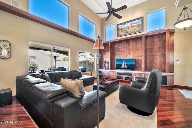 living room with a towering ceiling, ceiling fan, and wood-type flooring