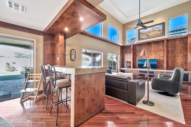 interior space featuring ceiling fan, wooden walls, hardwood / wood-style flooring, a center island, and a breakfast bar area