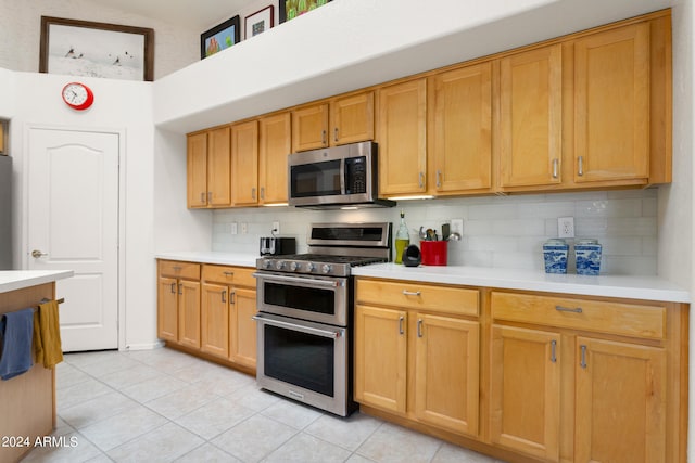 kitchen with appliances with stainless steel finishes, backsplash, and light tile floors