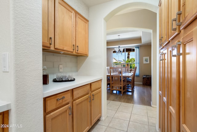 kitchen with a notable chandelier, tasteful backsplash, light tile floors, and pendant lighting