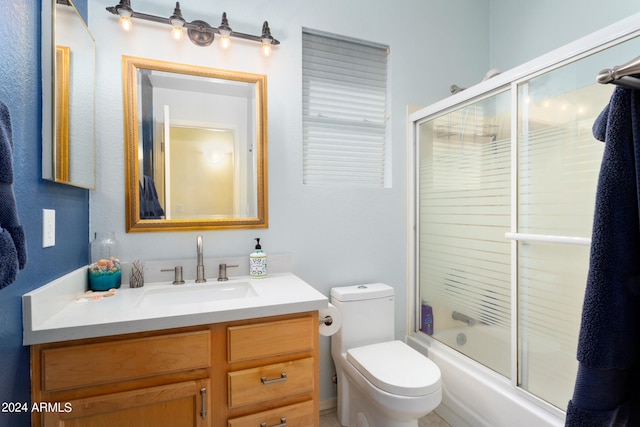 full bathroom featuring vanity with extensive cabinet space, toilet, and shower / bath combination with glass door