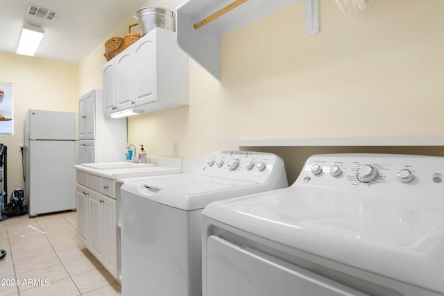 laundry area with cabinets, light tile floors, sink, and separate washer and dryer