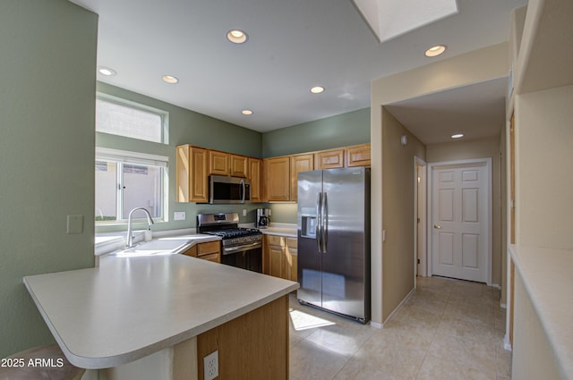 kitchen featuring light tile patterned flooring, appliances with stainless steel finishes, kitchen peninsula, and sink