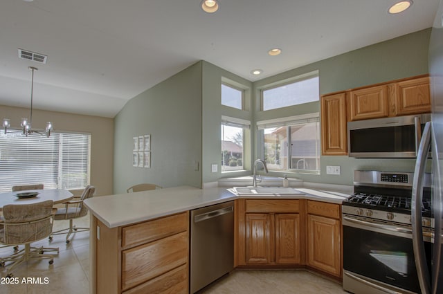 kitchen featuring sink, an inviting chandelier, appliances with stainless steel finishes, kitchen peninsula, and pendant lighting