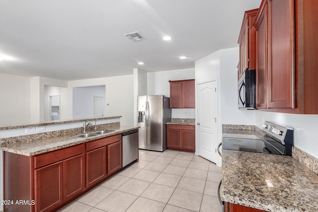 kitchen featuring an island with sink, light stone counters, light tile patterned floors, black appliances, and sink